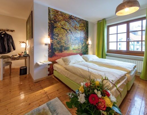 Themenzimmer: Waldheimat Helles Schlafzimmer mit zwei Betten, einer Blumenarrangement und einer Wandmalerei von Bäumen.