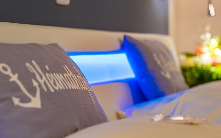 Themenzimmer: Heimathafen Zwei Kissen mit Anker-Motiv und blauer LED-Beleuchtung im Hintergrund.