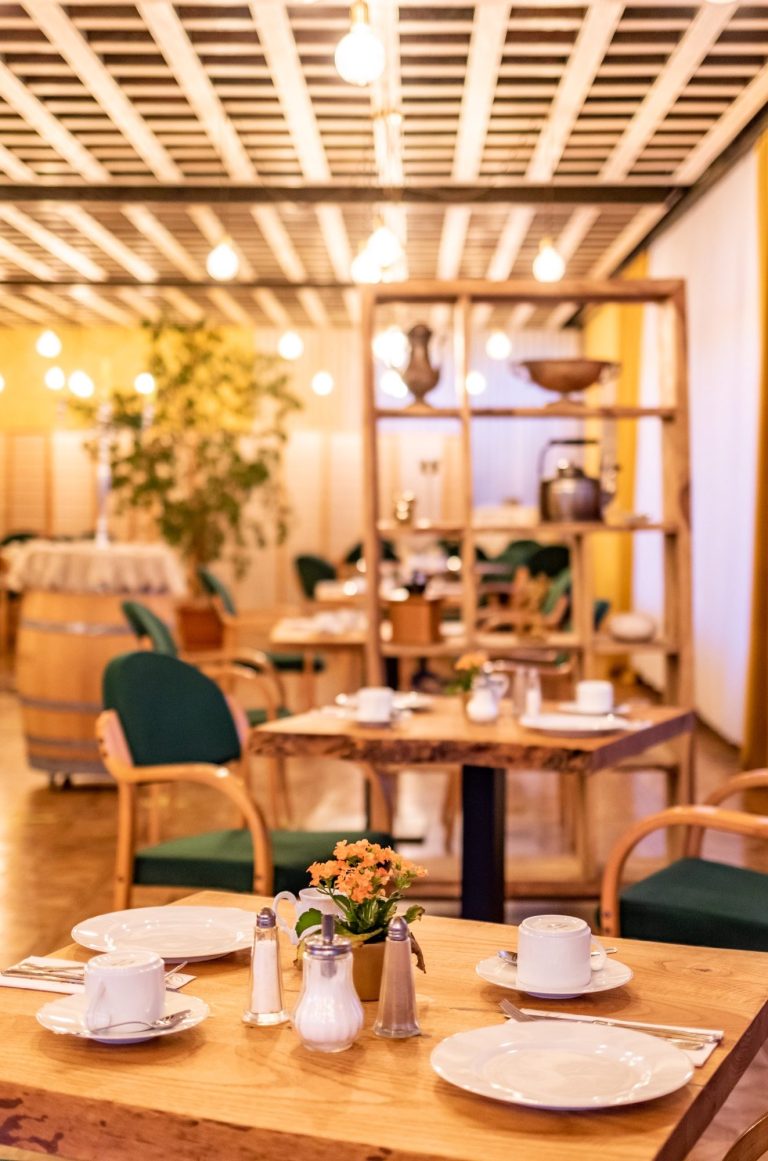 Frühstückssaal Hotel Goldflair Gemütlicher Fürhstückssaal mit Holzdekor, Blumenmitteltisch und gedeckten Tischen.